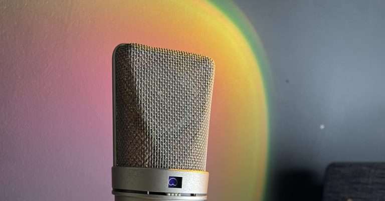 Close-up of a neumann microphone in a shock mount, set against a backdrop with soft lighting, ready for vocal recording in a studio.